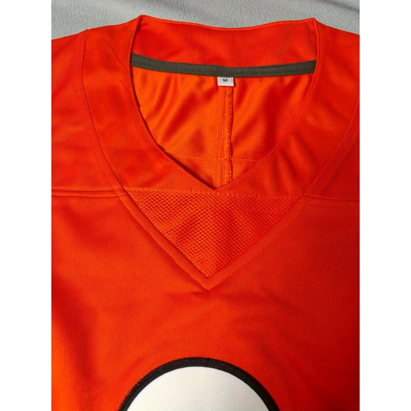 Close-up of a bright orange football jersey with a V-neck collar, mesh panel, and a partial white circular graphic outlined in black at the bottom.